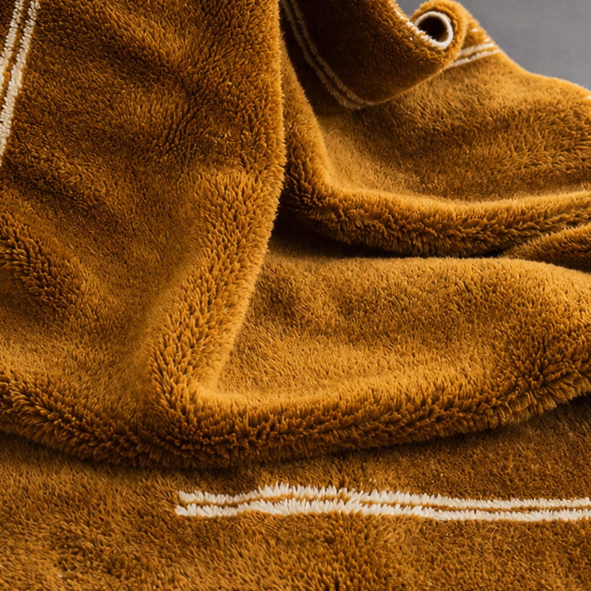 Close-up of Atrium Moroccan wool rug showing high-pile amber wool texture and ivory border line.