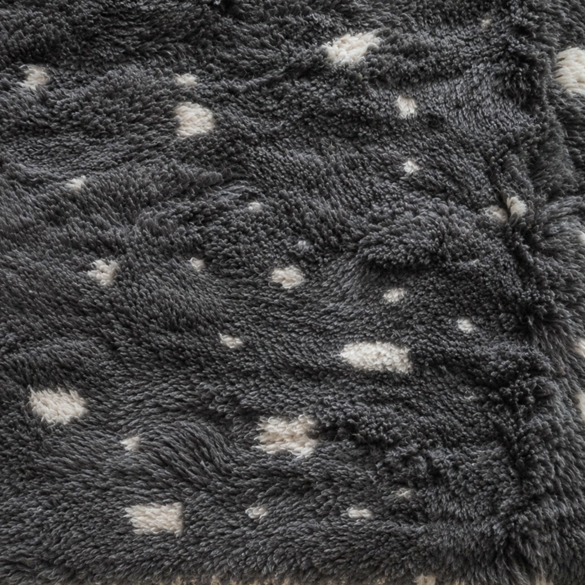 Close-up of Constellation handmade Moroccan wool rug with charcoal grey pile and irregular ivory dots