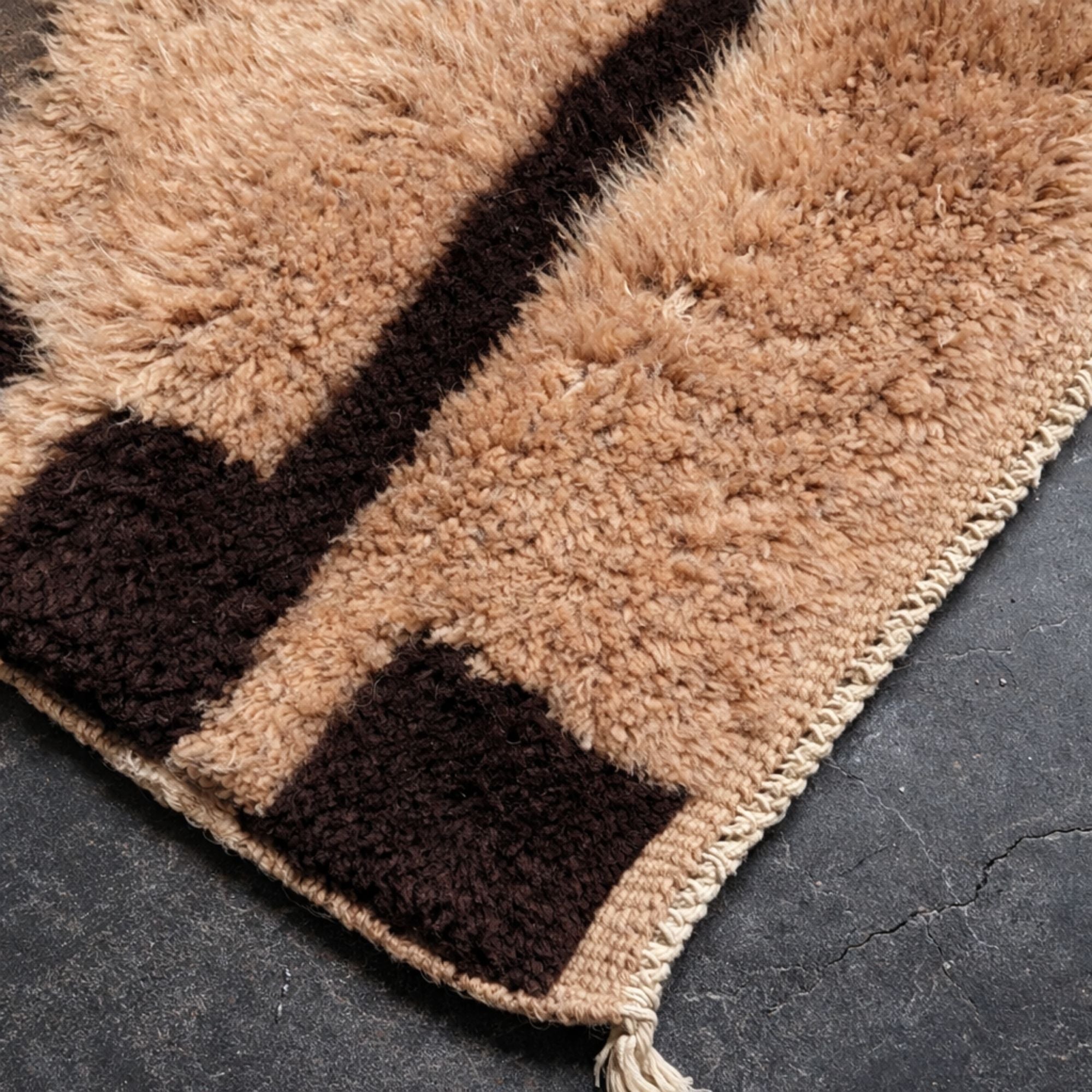 Close-up of the Cadence Moroccan wool rug showing thick handwoven texture, black border detailing, and handmade tassel edge.