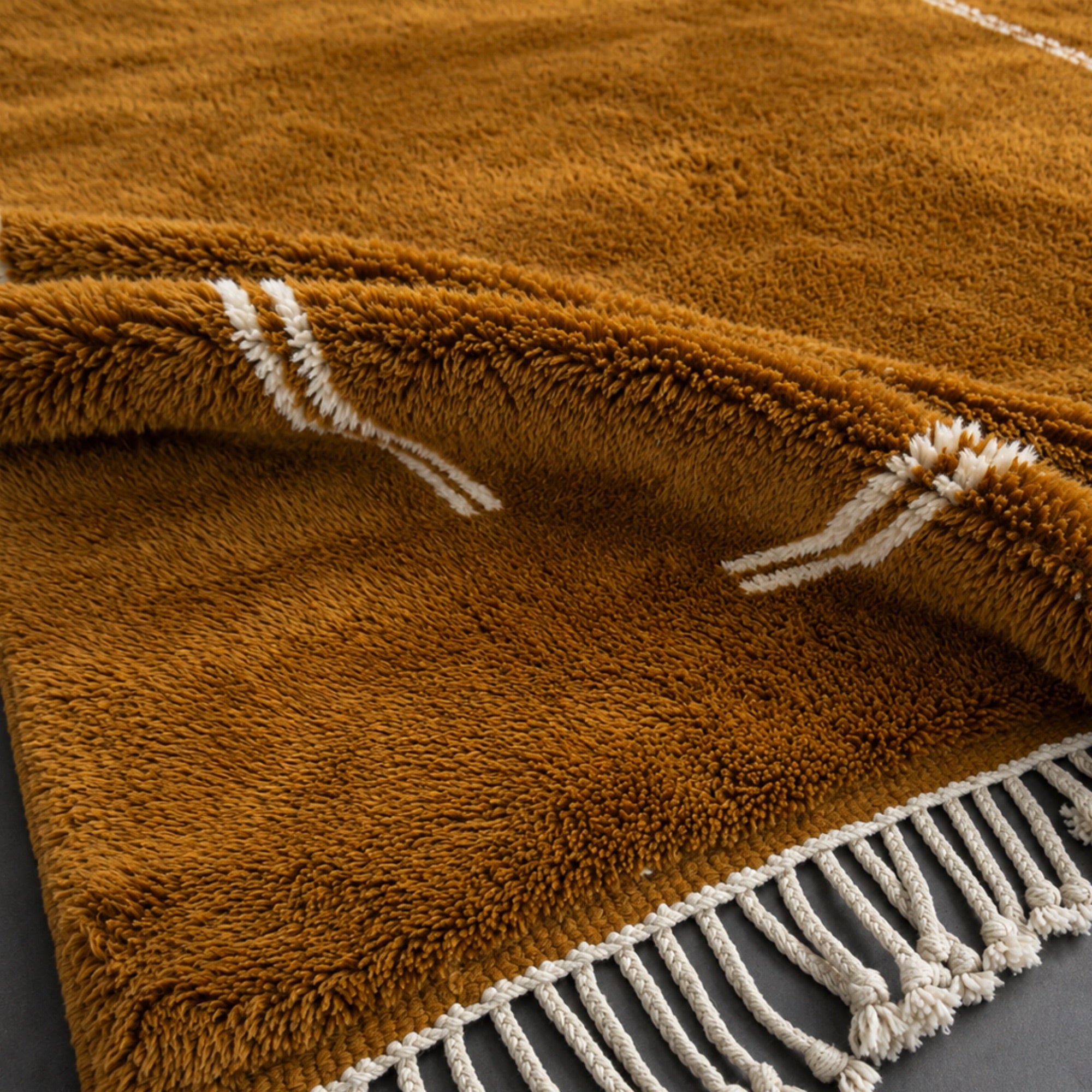 Detail of Atrium handmade Moroccan wool rug corner showing fringe and border stitching.