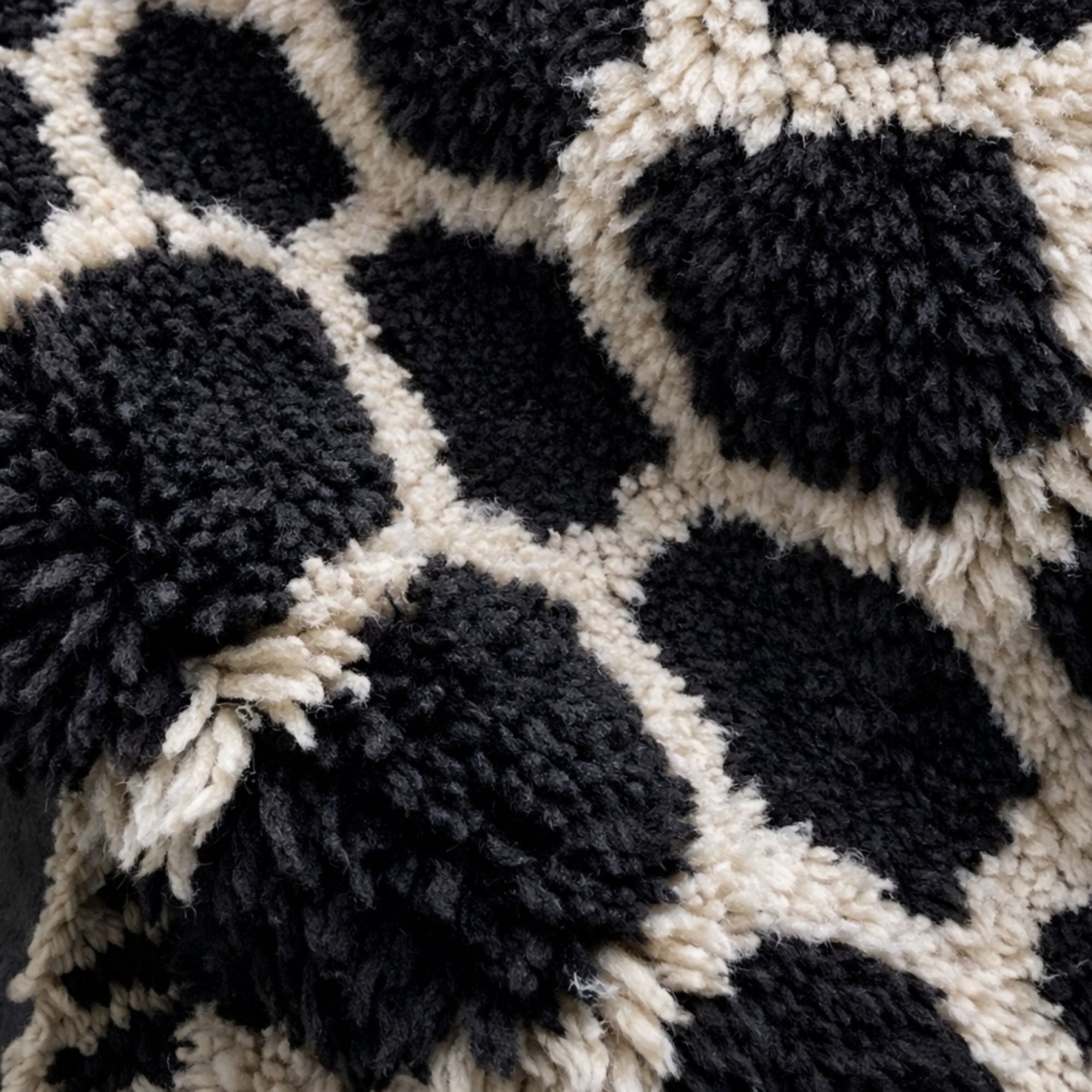 Detailed view of a luxury Moroccan Beni Mrirt rug showing dense high-pile black wool motifs and soft ivory wool outlines. The handmade texture and sculptural surface highlight artisanal craftsmanship.