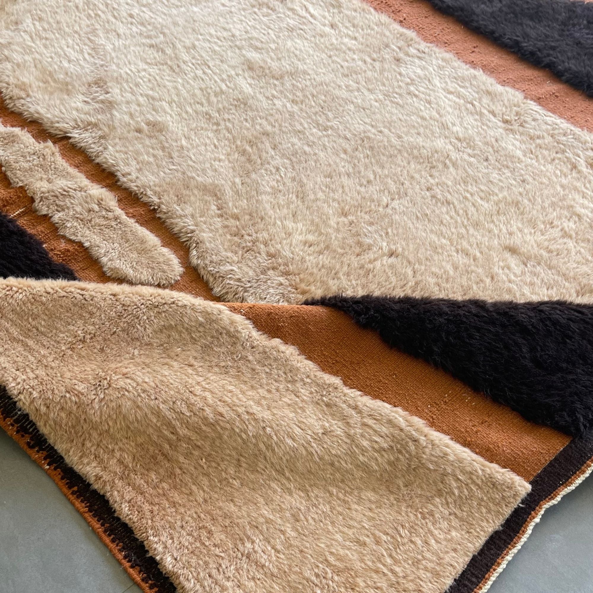 Handwoven Moroccan wool rug, Totem no. 01 design, folded detail showing cream and black shape edges.
