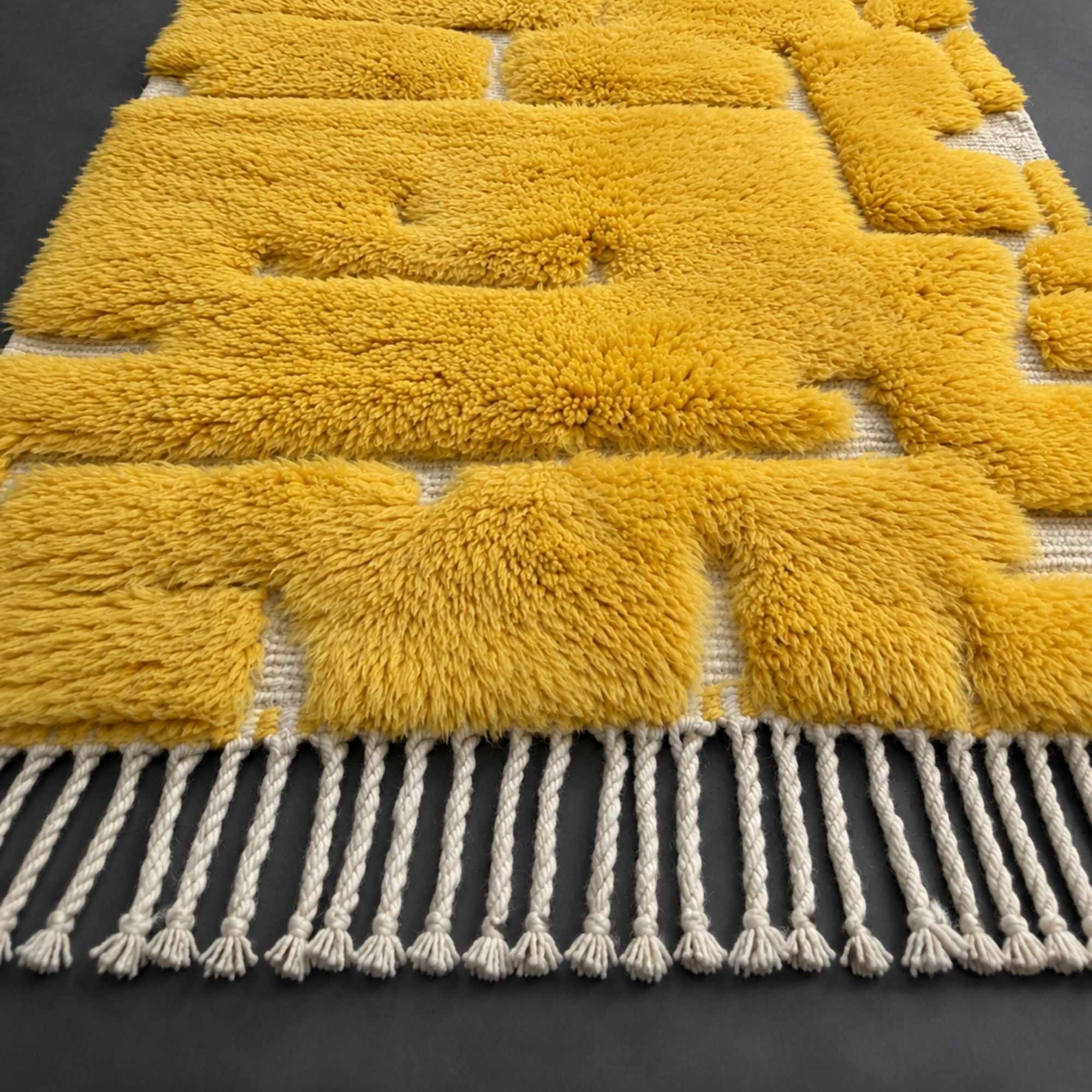 Handwoven Moroccan wool rug, Solarium design, corner detail showing block pattern and braided fringe.