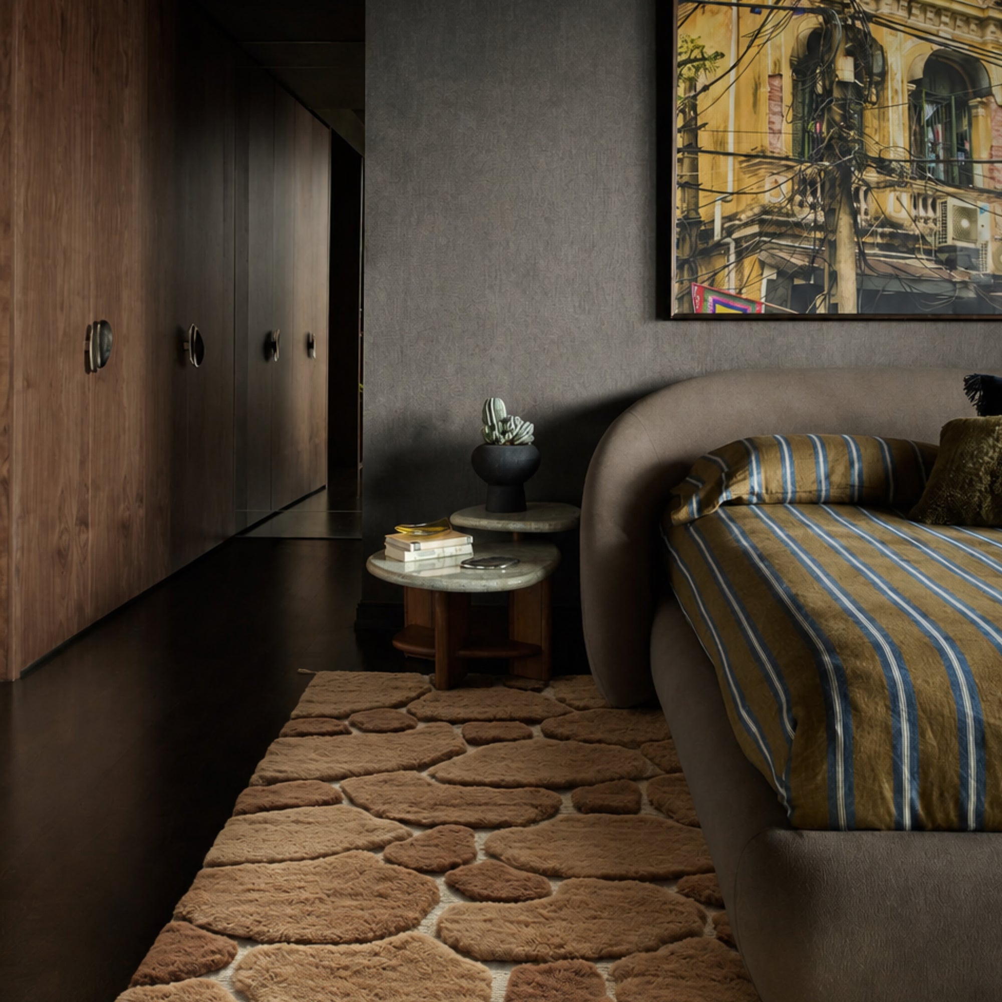 Sediment handmade Moroccan wool rug styled as a bedside runner in a dark, moody bedroom interior.