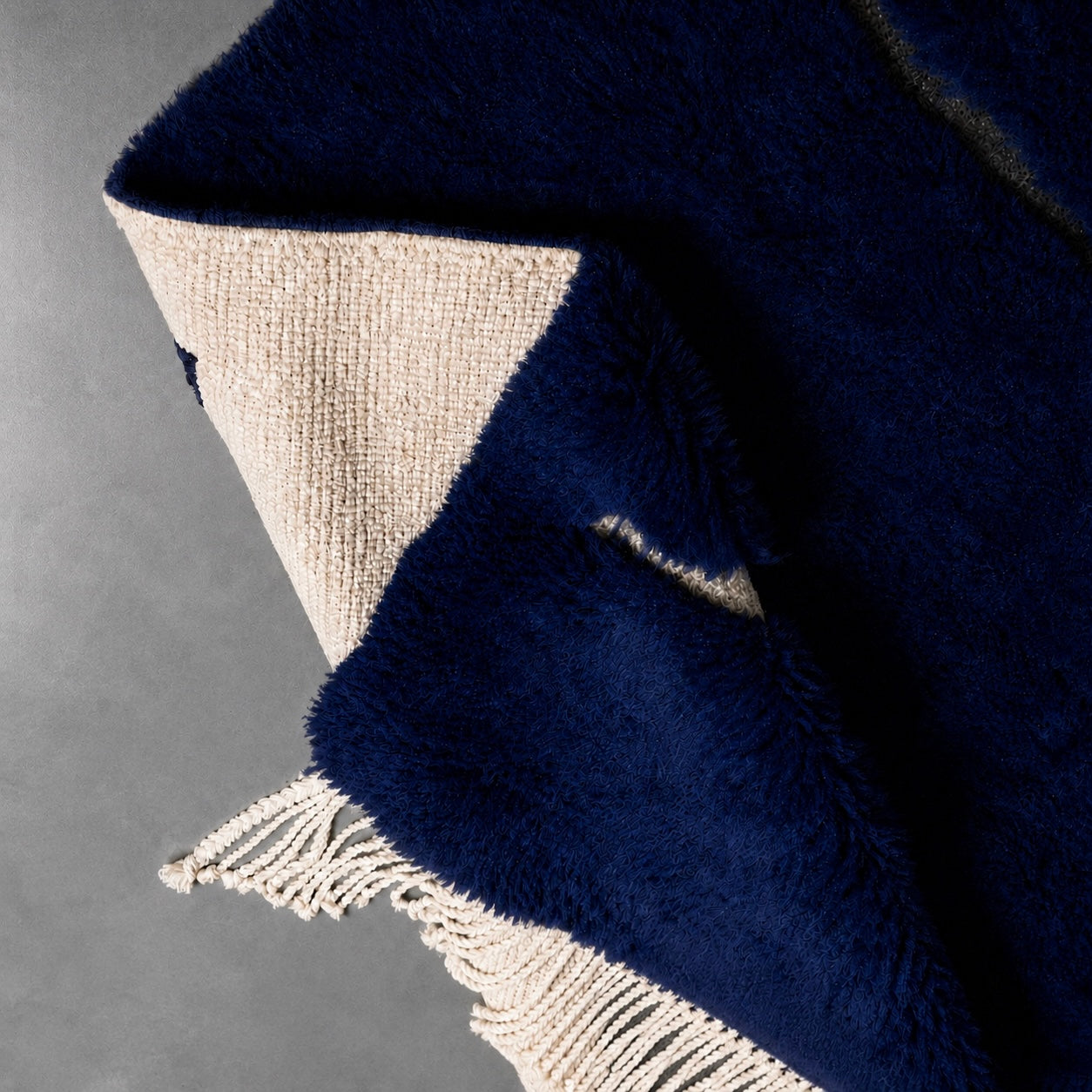 Close-up detail of Trace No. 01 showcasing the rich bleu-noir wool pile and handwoven ivory line motif.