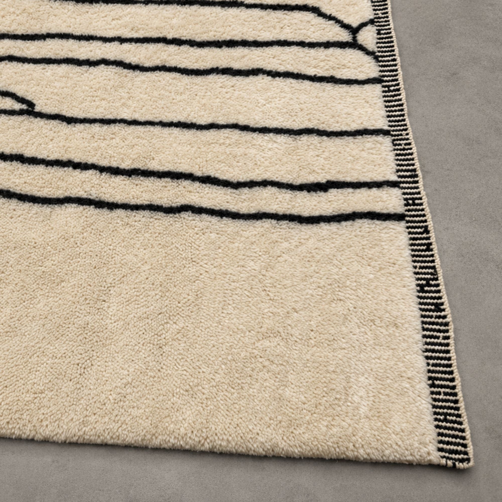 Close-up of Reed Line Moroccan wool rug showing high-pile texture and crossing black line detail.