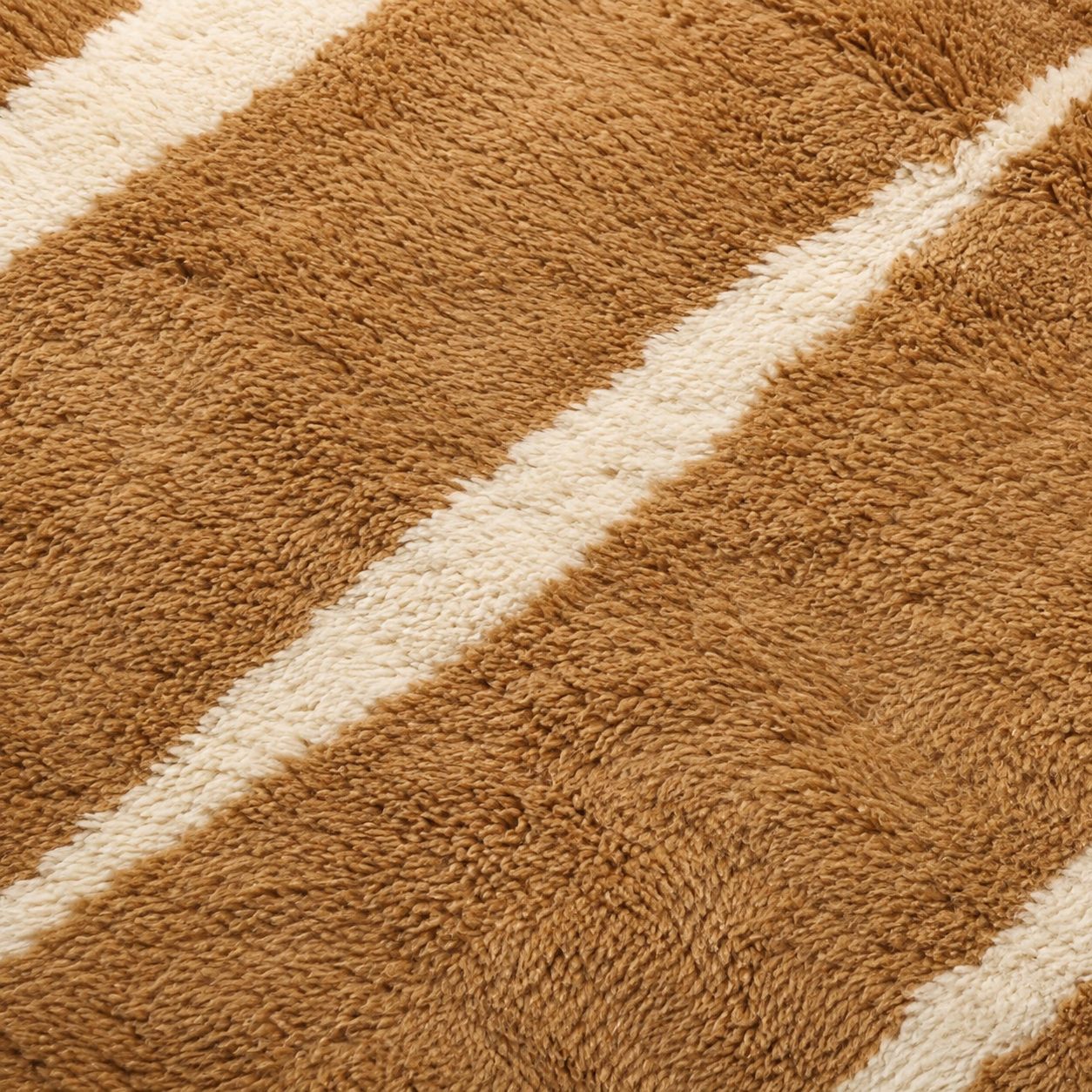 Close-up of Veil No. 01 showing the dense hand-knotted wool pile, natural camel tones, and irregular ivory stripe detail characteristic of Moroccan craftsmanship.