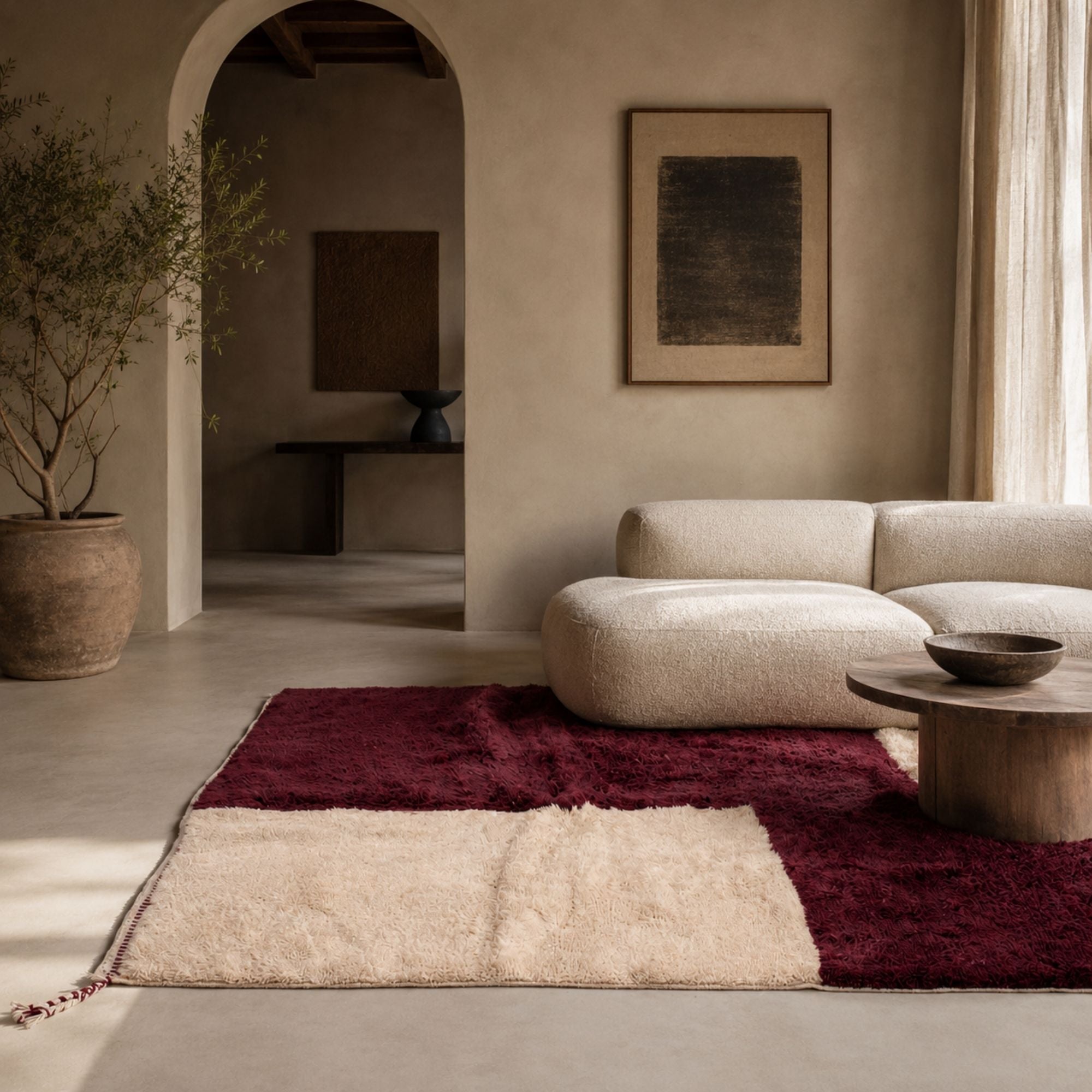 Contemporary living room featuring a handmade burgundy and cream Moroccan rug with bold checkerboard geometry, soft wool pile, and warm minimalist interior styling.