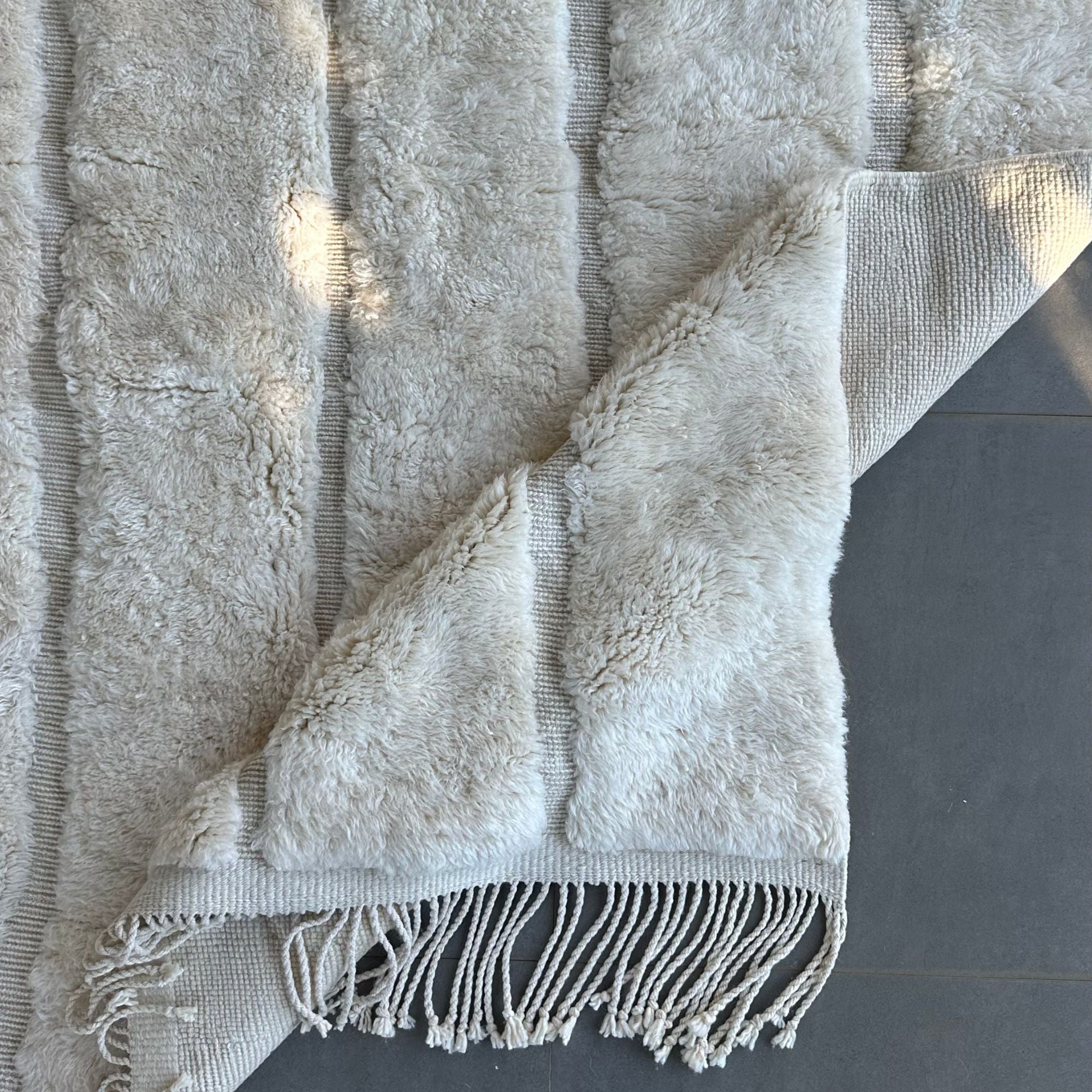 esert Serenity, a handcrafted white Moroccan rug with subtle textured patterns, made of 100% natural wool, displayed against a neutral backdrop to highlight its minimalist and elegant design