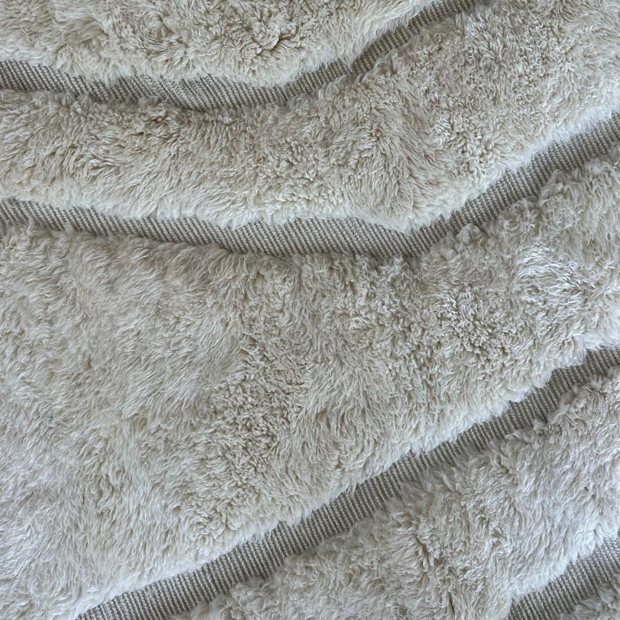 esert Serenity, a handcrafted white Moroccan rug with subtle textured patterns, made of 100% natural wool, displayed against a neutral backdrop to highlight its minimalist and elegant design
