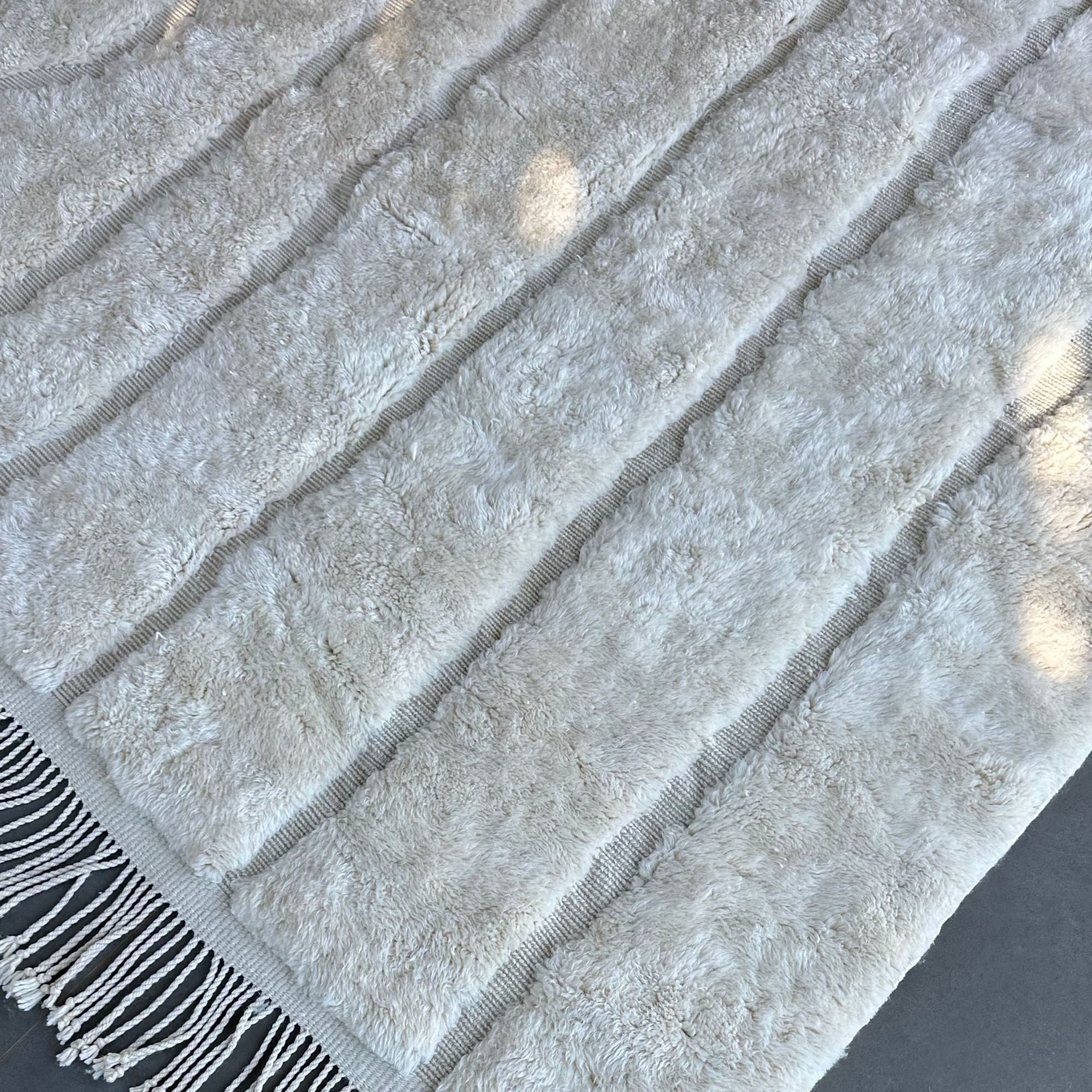 esert Serenity, a handcrafted white Moroccan rug with subtle textured patterns, made of 100% natural wool, displayed against a neutral backdrop to highlight its minimalist and elegant design