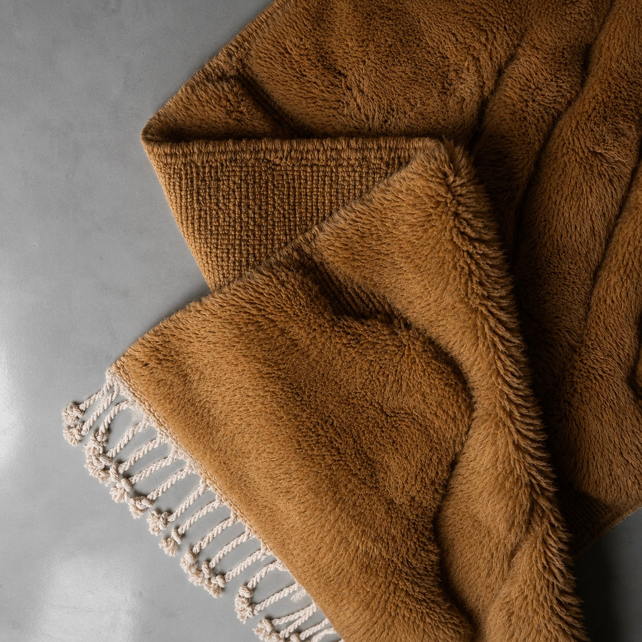 Folded corner of Relief No. 01 handwoven Moroccan runner revealing dense natural wool pile, woven backing, ivory tassels, and soft camel brown tones with exceptional texture and craftsmanship.