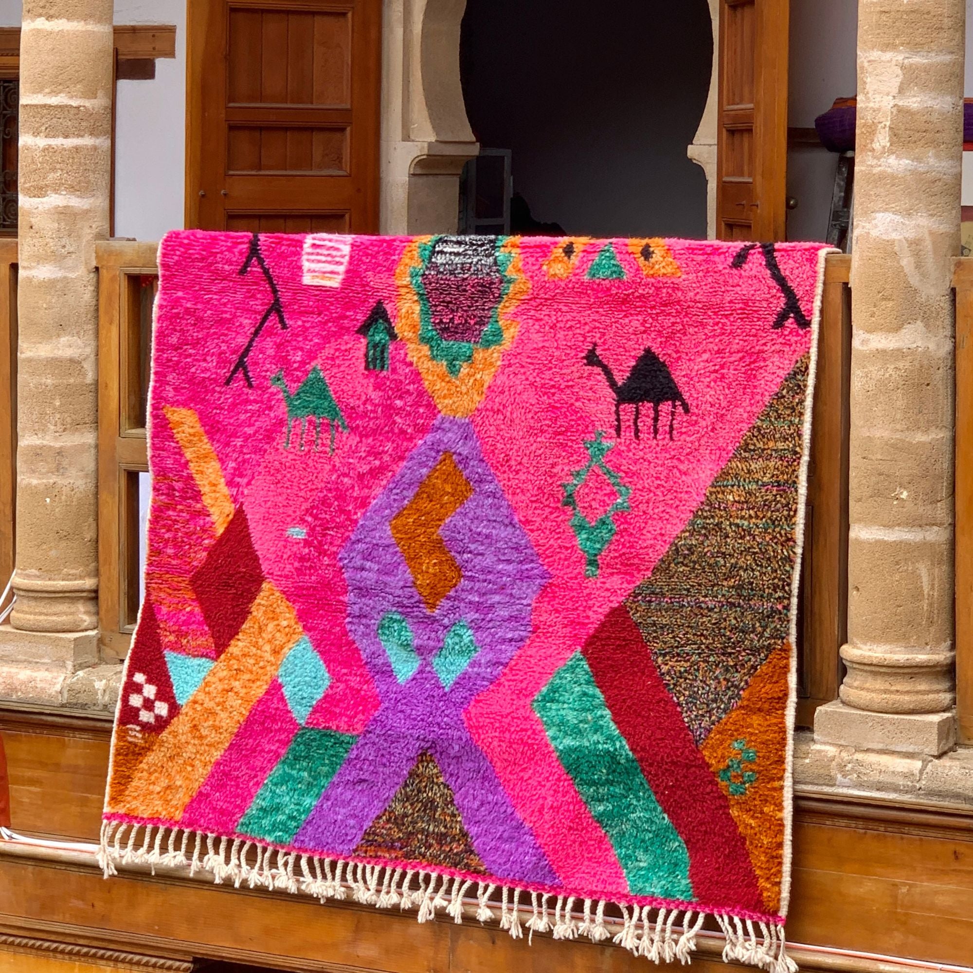 Desert Dance handmade wool rug in stock with a pink base and multicolor design, featuring Berber women's secret language, handwoven by Berber artisans