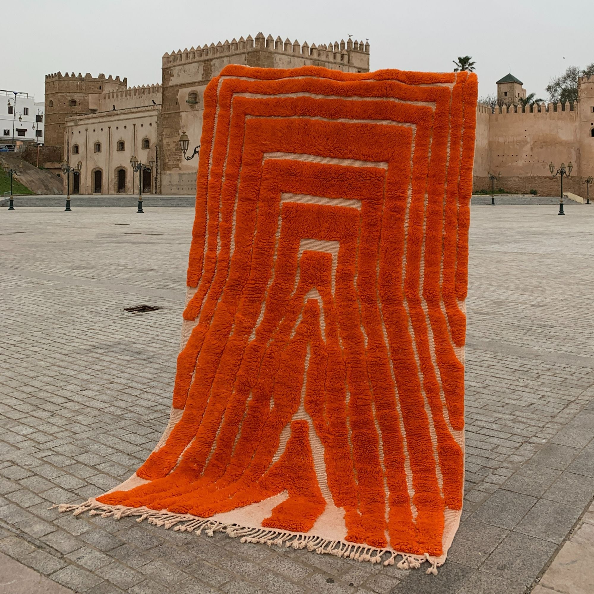 Sahara Symphony Moroccan rug in vibrant orange with a textured design revealing a white base