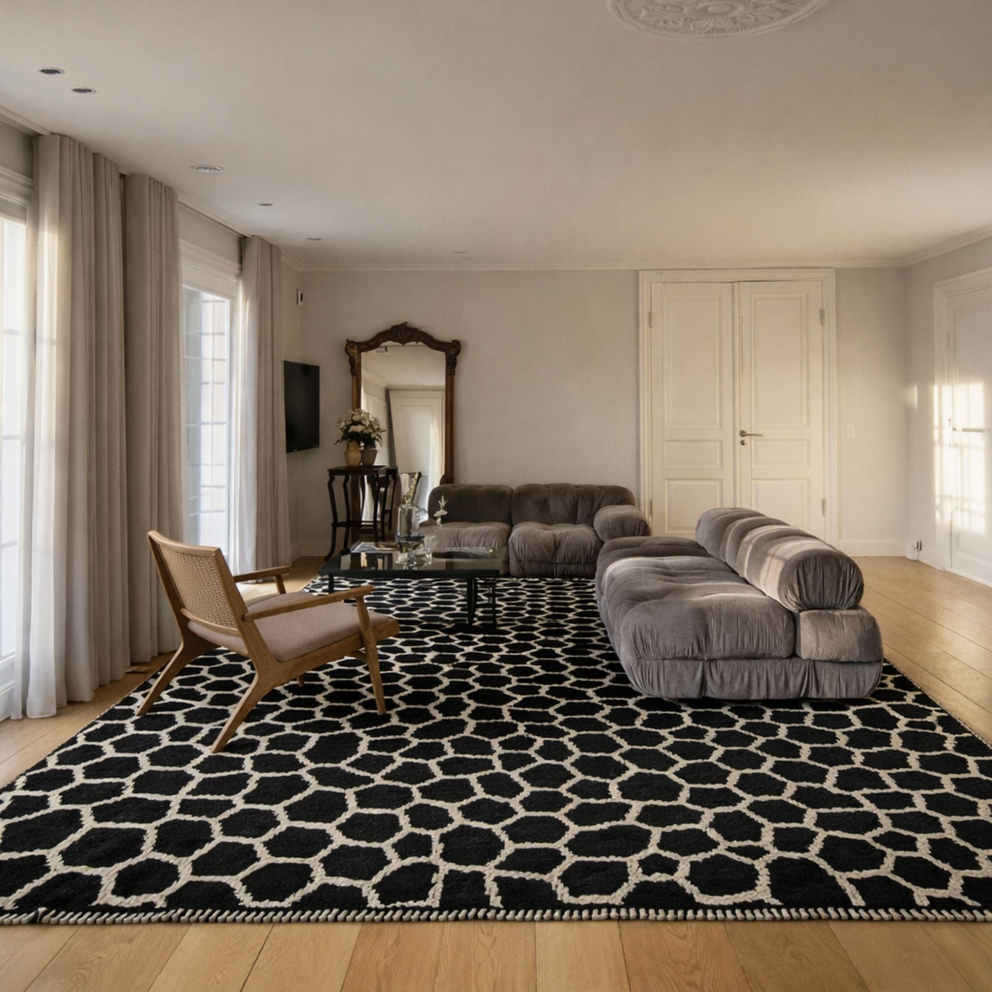 Luxury living room styled with a handmade Moroccan wool rug featuring black pebble-like motifs on an ivory background. The statement rug anchors contemporary seating and warm natural light.