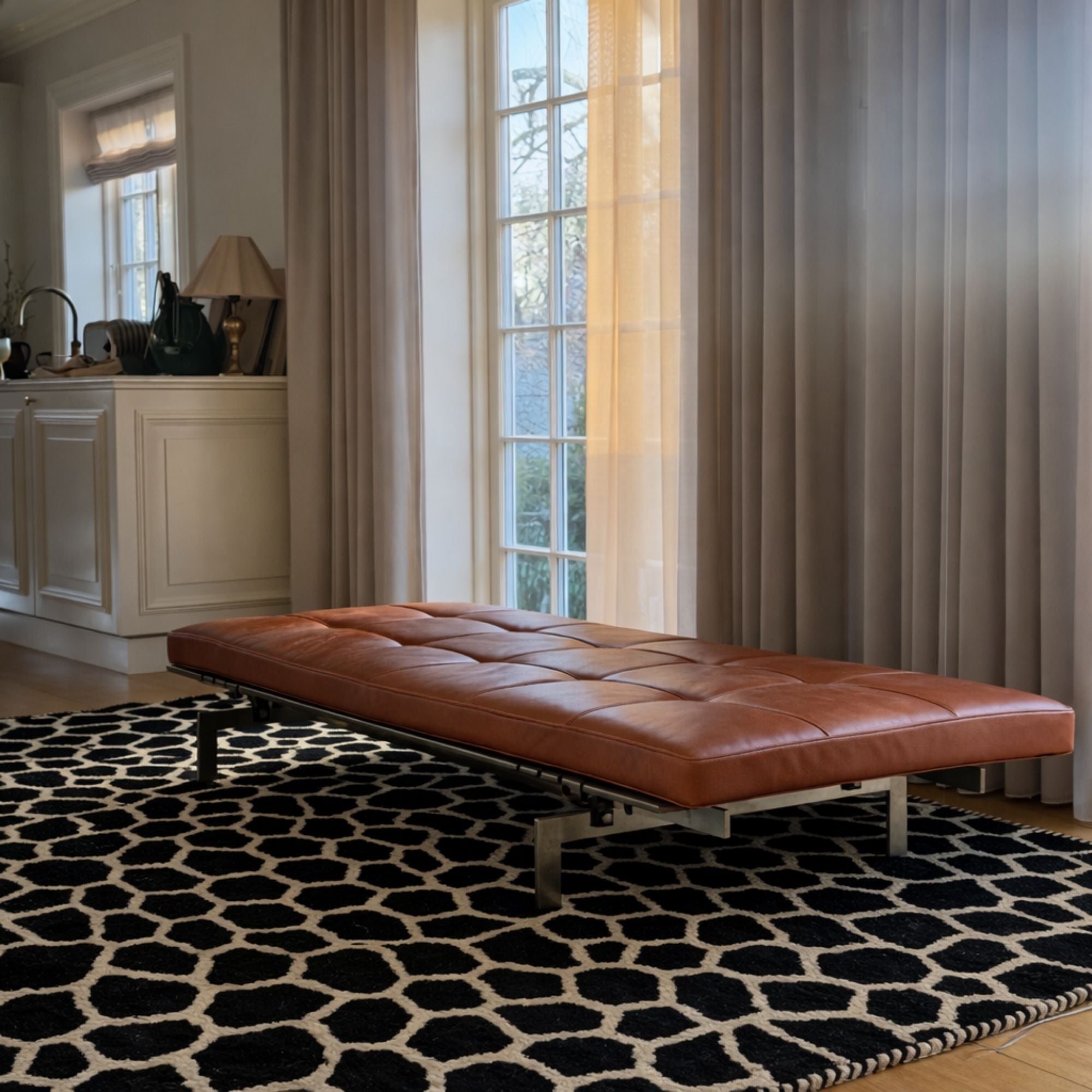 Modern interior featuring a handcrafted Moroccan Beni Mrirt rug beneath a cognac leather bench. The black and ivory organic pattern adds bold contrast and texture to the minimalist space.