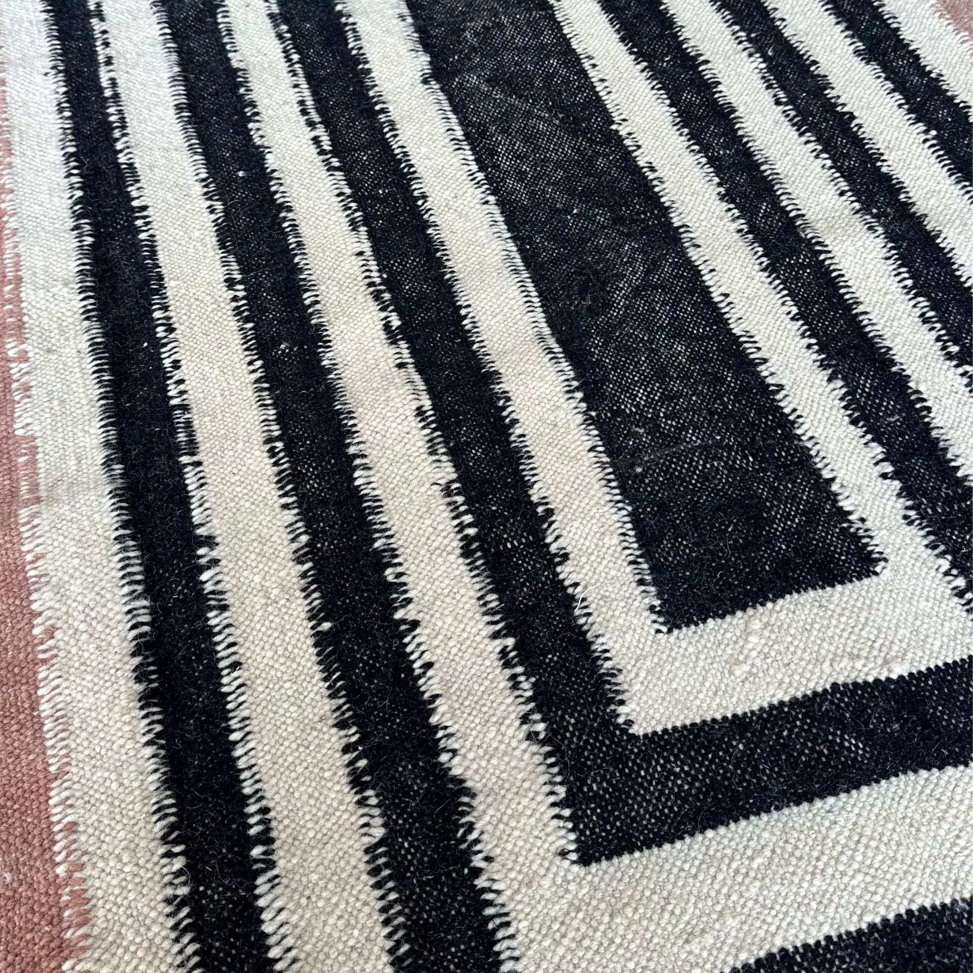 Mystique Beauty flat weave rug with black and brown geometrical patterns on an off-white base.