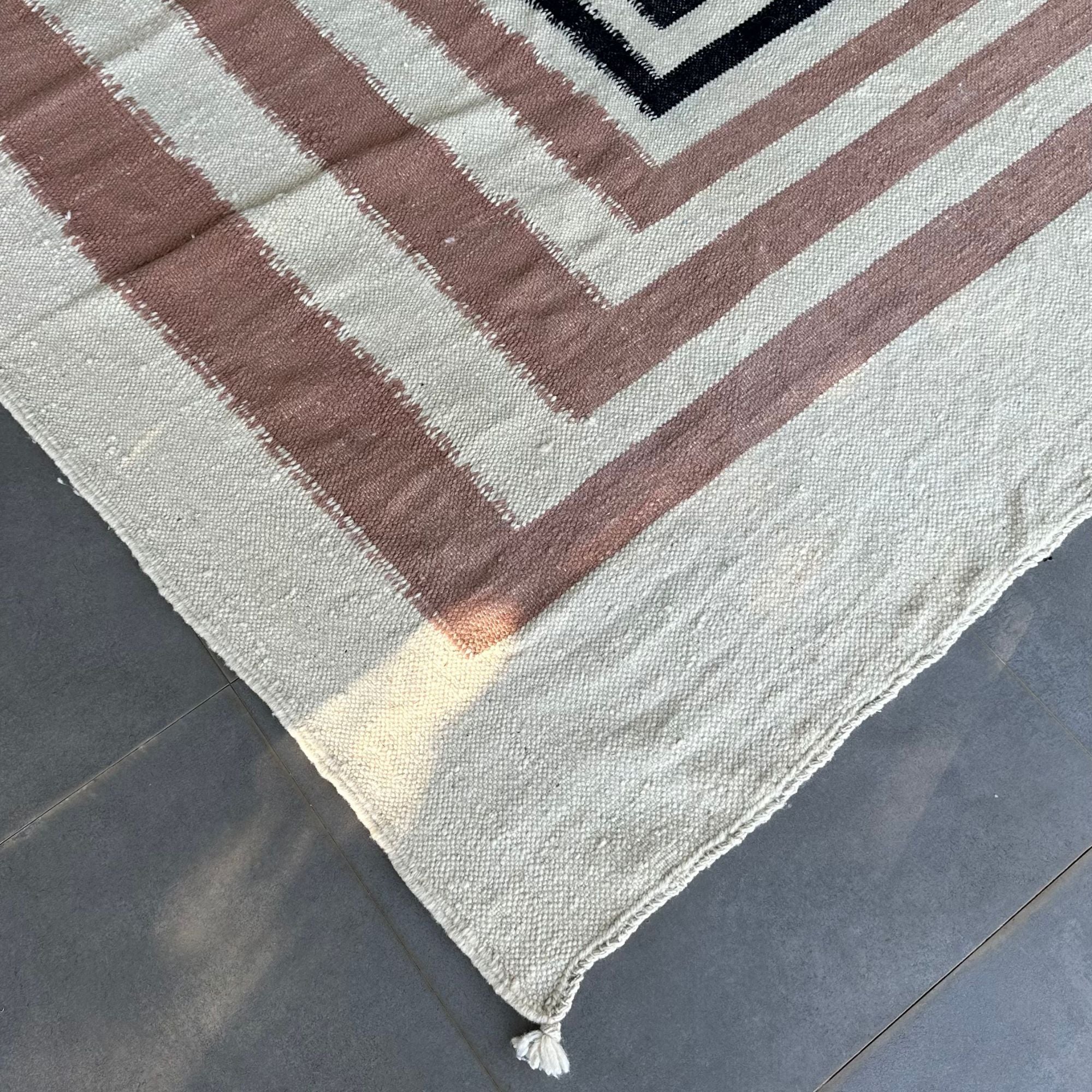 Mystique Beauty flat weave rug with black and brown geometrical patterns on an off-white base.