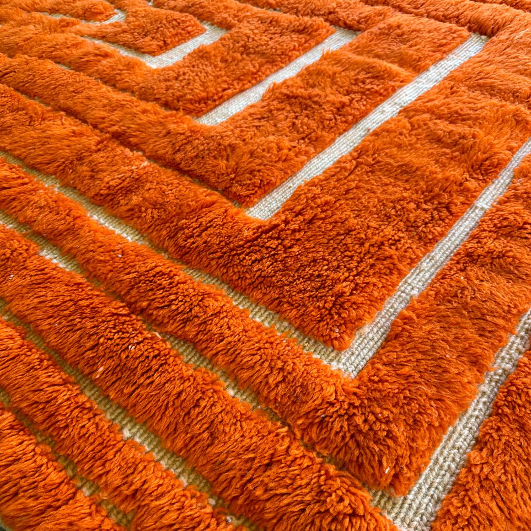 Sahara Symphony Moroccan rug in vibrant orange with a textured design revealing a white base