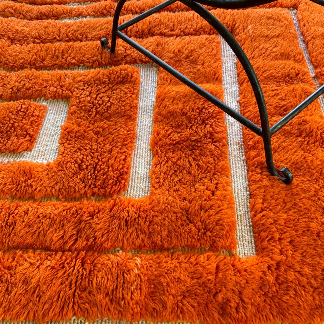 Sahara Symphony Moroccan rug in vibrant orange with a textured design revealing a white base