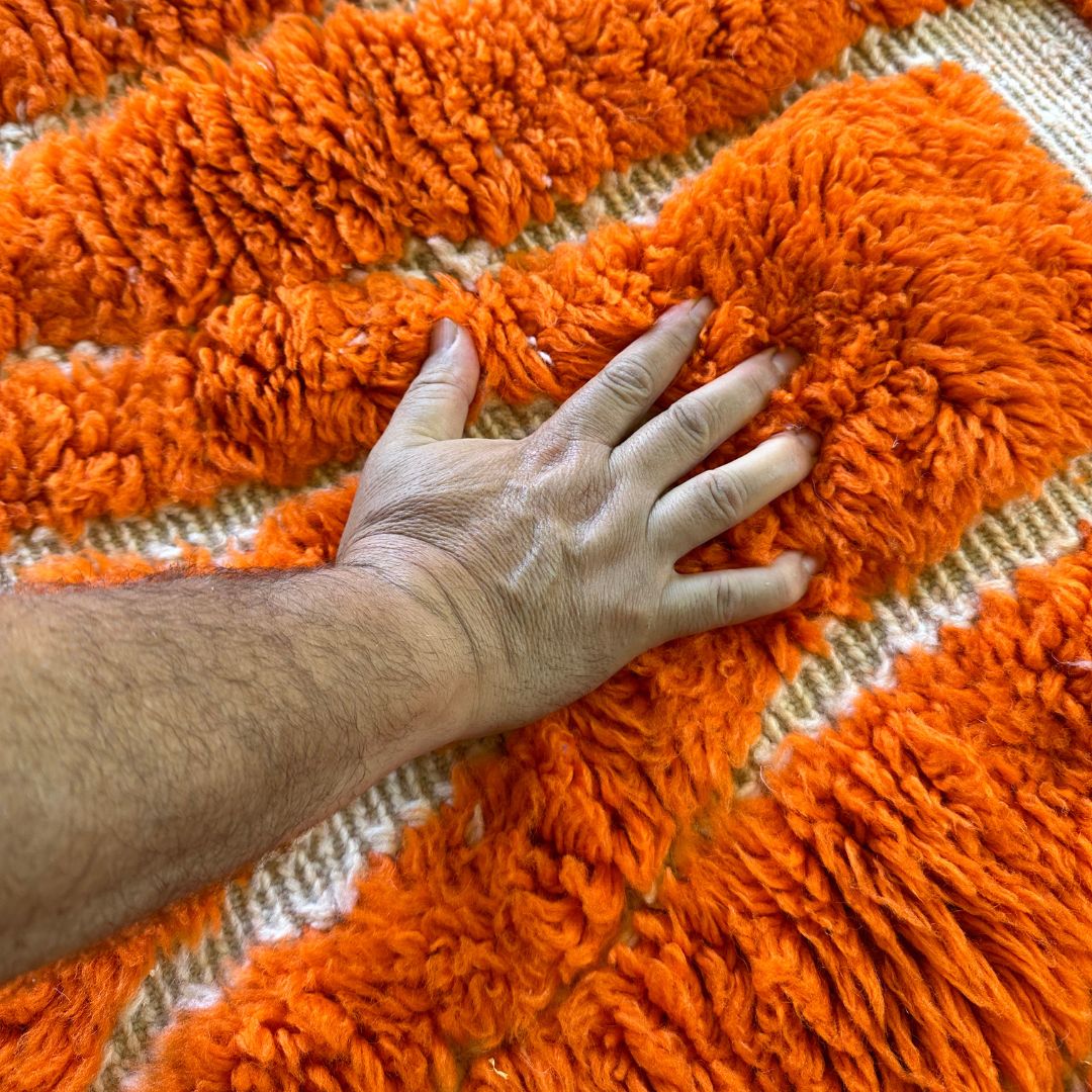 Sahara Symphony Moroccan rug in vibrant orange with a textured design revealing a white base