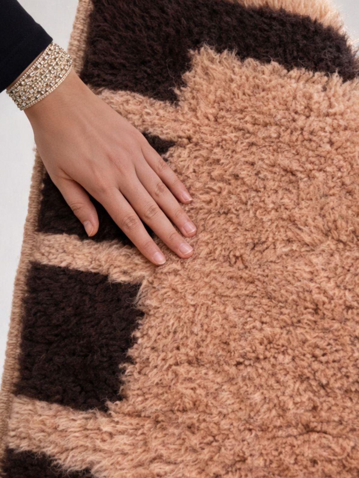 Close-up of hand touching a handwoven Moroccan Berber wool rug, highlighting soft texture and artisanal craftsmanship